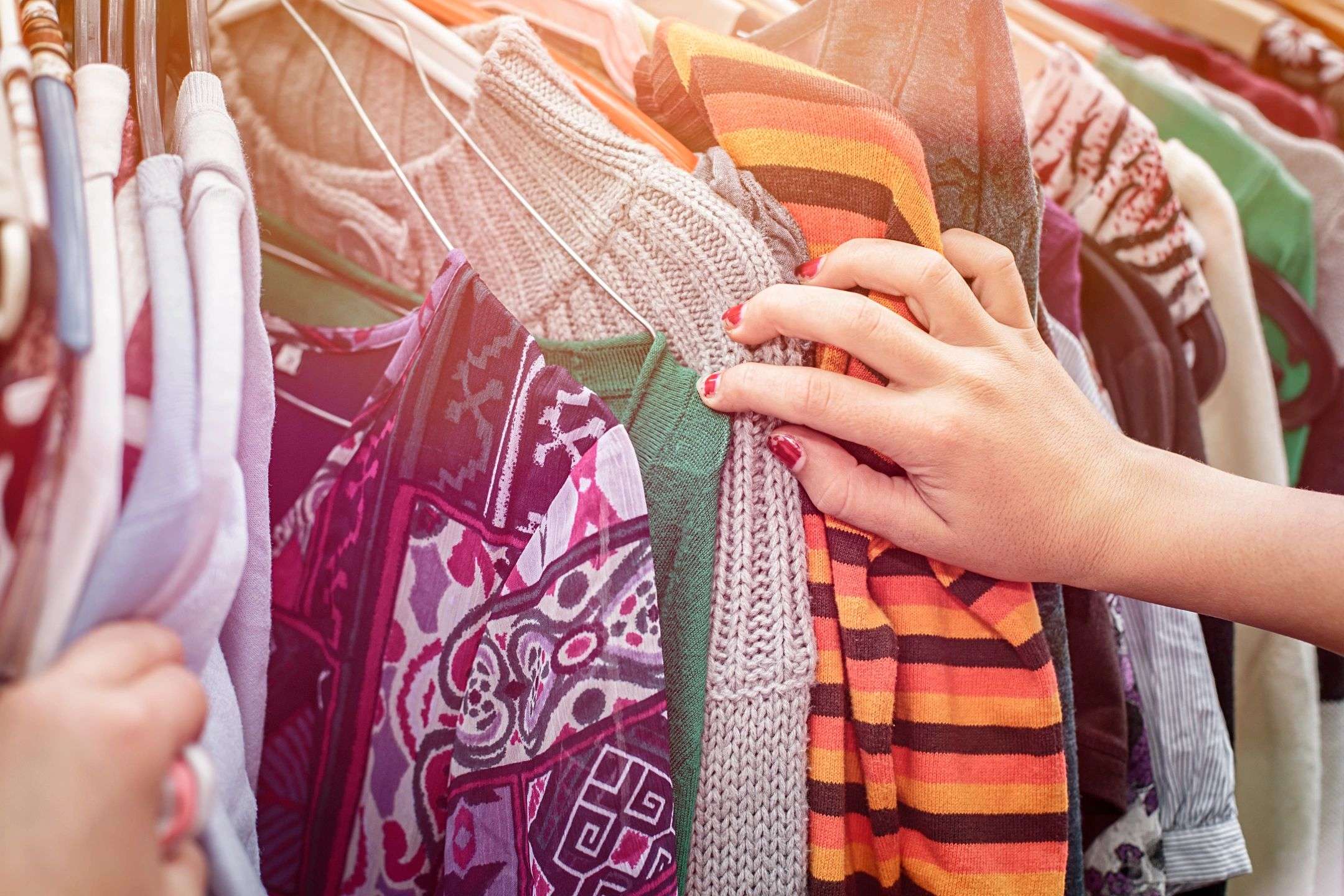 Hands sorting through hanging clothes