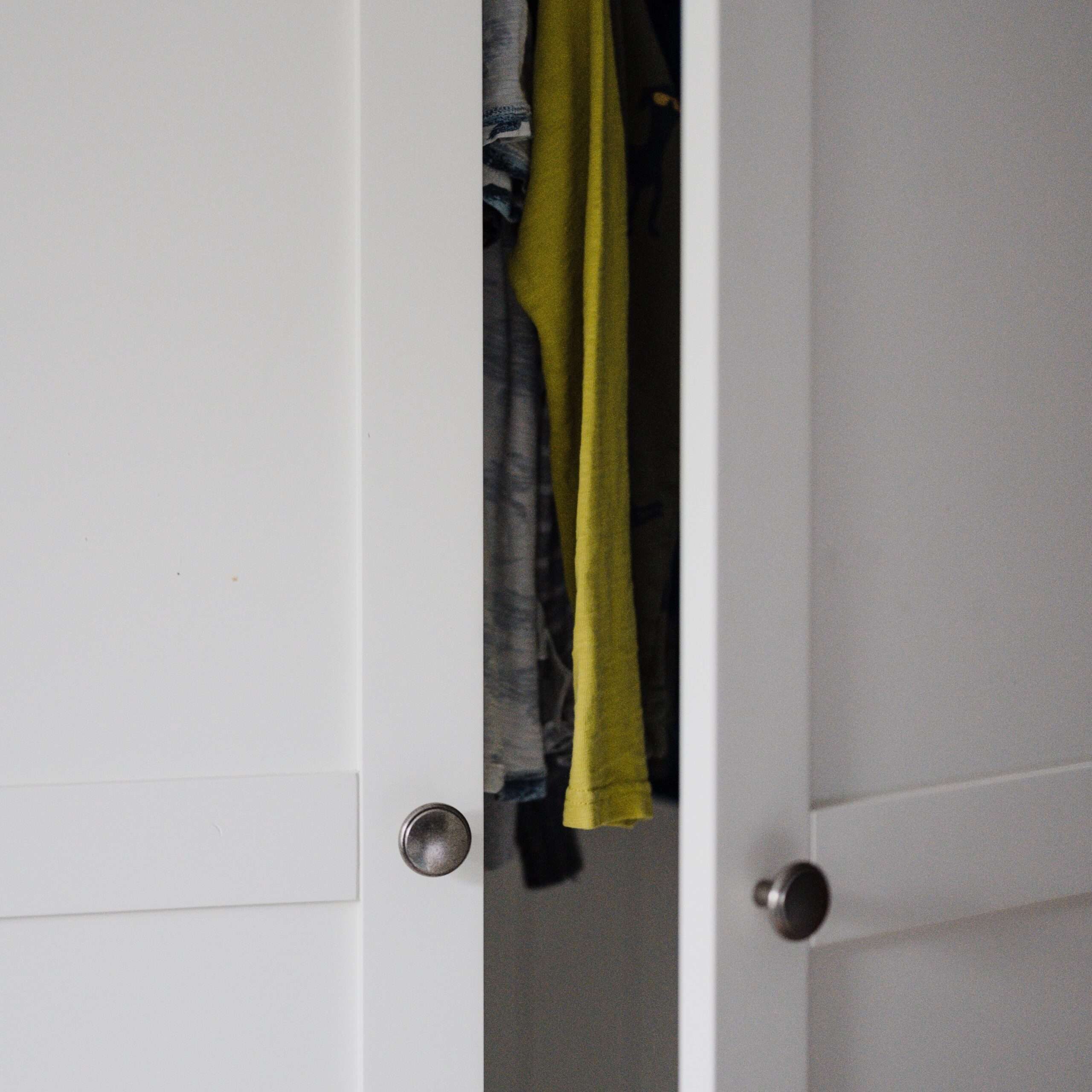 Closet door partially opened with clothes inside